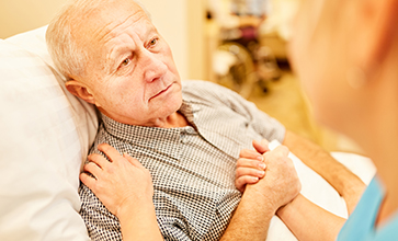 Nursing consoles a sick senior man in a nursing home or in home care